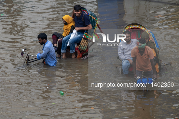 Passengers are riding on a rickshaw to go through a waterlogged street after heavy rain in Dhaka, Bangladesh, on July 12, 2024. 