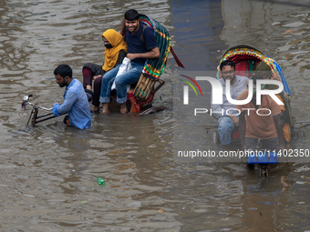 Passengers are riding on a rickshaw to go through a waterlogged street after heavy rain in Dhaka, Bangladesh, on July 12, 2024. (