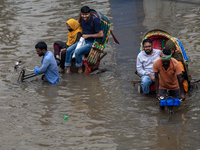 Passengers are riding on a rickshaw to go through a waterlogged street after heavy rain in Dhaka, Bangladesh, on July 12, 2024. (