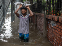 People are wading through a waterlogged street after heavy rain in Dhaka, Bangladesh, on July 12, 2024. (