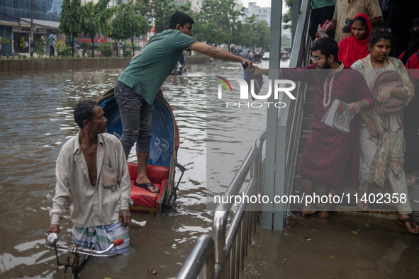 Passengers are riding on a rickshaw to go through a waterlogged street after heavy rain in Dhaka, Bangladesh, on July 12, 2024. 