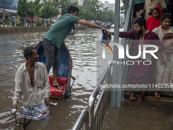 Passengers are riding on a rickshaw to go through a waterlogged street after heavy rain in Dhaka, Bangladesh, on July 12, 2024. (