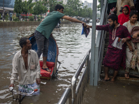 Passengers are riding on a rickshaw to go through a waterlogged street after heavy rain in Dhaka, Bangladesh, on July 12, 2024. (