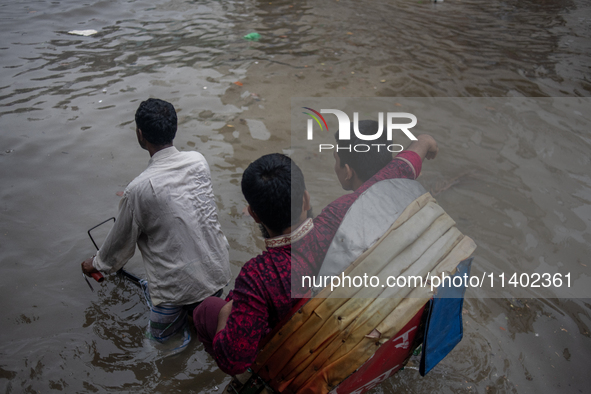 Passengers are riding on a rickshaw to go through a waterlogged street after heavy rain in Dhaka, Bangladesh, on July 12, 2024. 