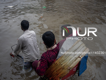 Passengers are riding on a rickshaw to go through a waterlogged street after heavy rain in Dhaka, Bangladesh, on July 12, 2024. (