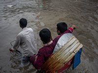 Passengers are riding on a rickshaw to go through a waterlogged street after heavy rain in Dhaka, Bangladesh, on July 12, 2024. (