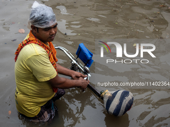 A rickshaw puller is waiting for passengers on a waterlogged street after heavy rain in Dhaka, Bangladesh, on July 12, 2024. (