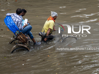 Passengers are riding on a rickshaw to go through a waterlogged street after heavy rain in Dhaka, Bangladesh, on July 12, 2024. (