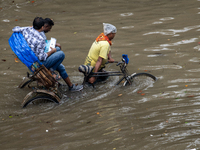 Passengers are riding on a rickshaw to go through a waterlogged street after heavy rain in Dhaka, Bangladesh, on July 12, 2024. (