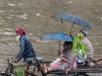 Passengers are riding on a rickshaw to go through a waterlogged street after heavy rain in Dhaka, Bangladesh, on July 12, 2024. (