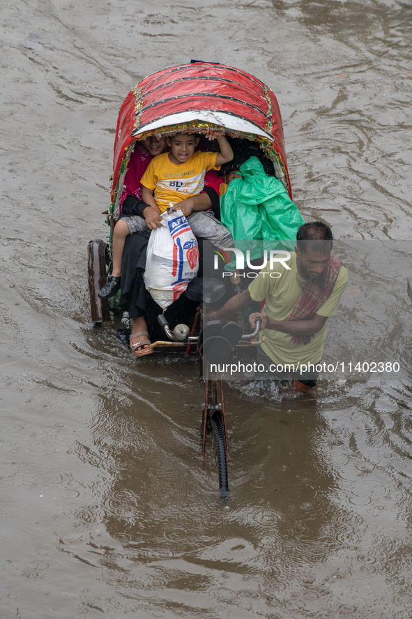 Passengers are riding on a rickshaw to go through a waterlogged street after heavy rain in Dhaka, Bangladesh, on July 12, 2024. 