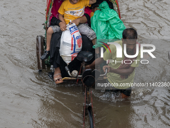 Passengers are riding on a rickshaw to go through a waterlogged street after heavy rain in Dhaka, Bangladesh, on July 12, 2024. (