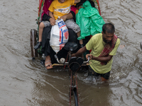 Passengers are riding on a rickshaw to go through a waterlogged street after heavy rain in Dhaka, Bangladesh, on July 12, 2024. (