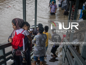 People are getting stuck on a footbridge after heavy rain is causing a waterlogged street in Dhaka, Bangladesh, on July 12, 2024. (