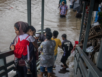 People are getting stuck on a footbridge after heavy rain is causing a waterlogged street in Dhaka, Bangladesh, on July 12, 2024. (