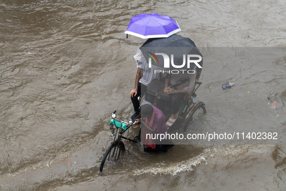 Passengers are riding on a rickshaw to go through a waterlogged street after heavy rain in Dhaka, Bangladesh, on July 12, 2024. 