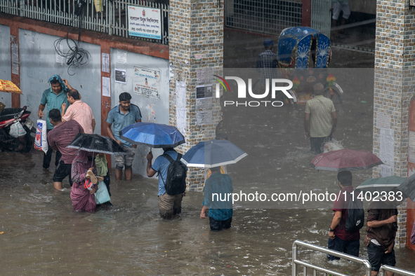 People are wading through a waterlogged street after heavy rain in Dhaka, Bangladesh, on July 12, 2024. 