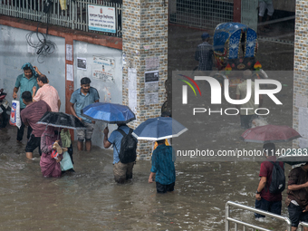 People are wading through a waterlogged street after heavy rain in Dhaka, Bangladesh, on July 12, 2024. (