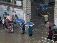 People are wading through a waterlogged street after heavy rain in Dhaka, Bangladesh, on July 12, 2024. (