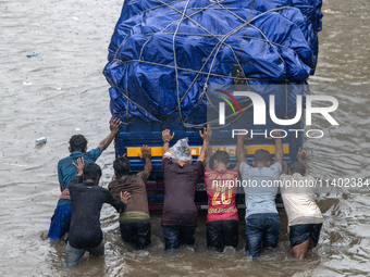 People are pushing a truck on a waterlogged street after heavy rain in Dhaka, Bangladesh, on July 12, 2024. (