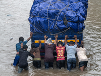 People are pushing a truck on a waterlogged street after heavy rain in Dhaka, Bangladesh, on July 12, 2024. (