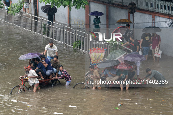 Passengers are riding in vans to go through a waterlogged street after heavy rain in Dhaka, Bangladesh, on Friday, July 12, 2024. 