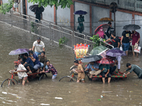 Passengers are riding in vans to go through a waterlogged street after heavy rain in Dhaka, Bangladesh, on Friday, July 12, 2024. (