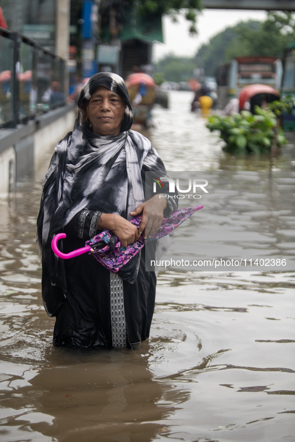 People are wading through a waterlogged street after heavy rain in Dhaka, Bangladesh, on July 12, 2024. 