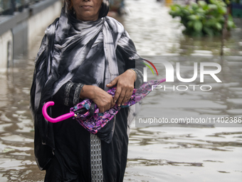 People are wading through a waterlogged street after heavy rain in Dhaka, Bangladesh, on July 12, 2024. (