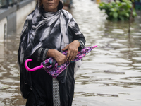 People are wading through a waterlogged street after heavy rain in Dhaka, Bangladesh, on July 12, 2024. (