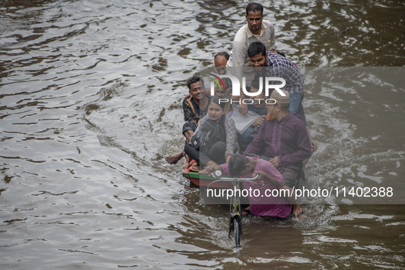 Passengers are riding in vans to go through a waterlogged street after heavy rain in Dhaka, Bangladesh, on Friday, July 12, 2024. 