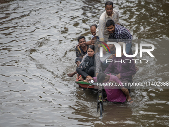 Passengers are riding in vans to go through a waterlogged street after heavy rain in Dhaka, Bangladesh, on Friday, July 12, 2024. (