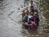 Passengers are riding in vans to go through a waterlogged street after heavy rain in Dhaka, Bangladesh, on Friday, July 12, 2024. (