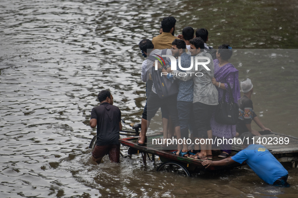 Passengers are riding in vans to go through a waterlogged street after heavy rain in Dhaka, Bangladesh, on Friday, July 12, 2024. 