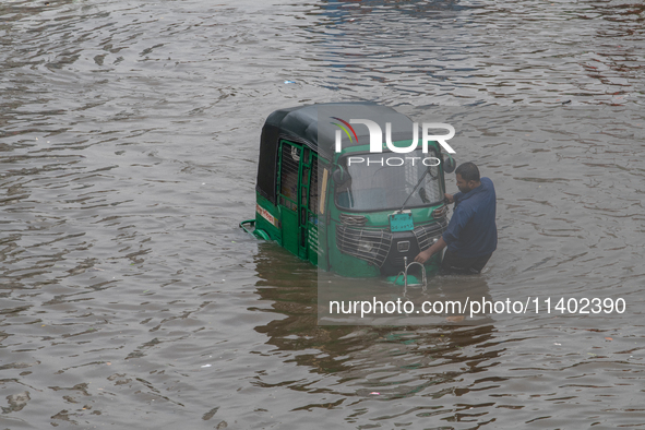 Vehicles are getting stuck on a waterlogged street after heavy rain in Dhaka, Bangladesh, on July 12, 2024. 