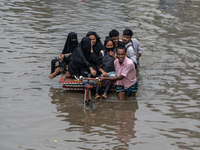 Passengers are riding in vans to go through a waterlogged street after heavy rain in Dhaka, Bangladesh, on Friday, July 12, 2024. (