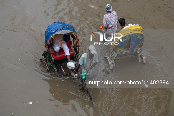 Passengers are riding on rickshaws to go through a waterlogged street after heavy rain in Dhaka, Bangladesh, on Friday, July 12, 2024. 