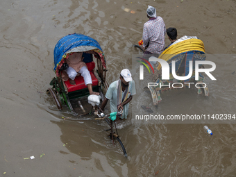 Passengers are riding on rickshaws to go through a waterlogged street after heavy rain in Dhaka, Bangladesh, on Friday, July 12, 2024. (