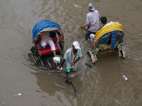 Passengers are riding on rickshaws to go through a waterlogged street after heavy rain in Dhaka, Bangladesh, on Friday, July 12, 2024. (