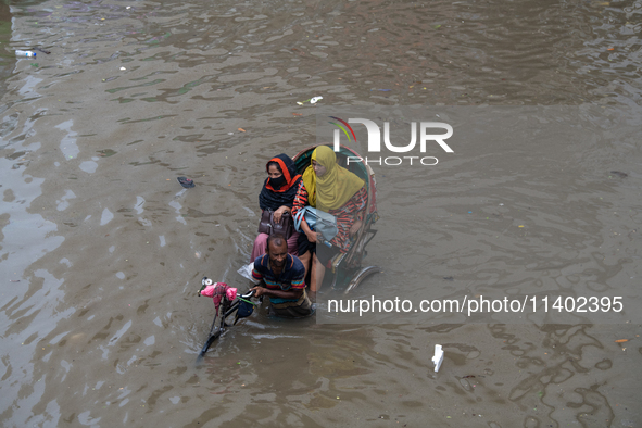 Passengers are riding on a rickshaw to go through a waterlogged street after heavy rain in Dhaka, Bangladesh, on July 12, 2024. 