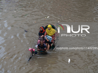 Passengers are riding on a rickshaw to go through a waterlogged street after heavy rain in Dhaka, Bangladesh, on July 12, 2024. (