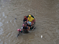 Passengers are riding on a rickshaw to go through a waterlogged street after heavy rain in Dhaka, Bangladesh, on July 12, 2024. (