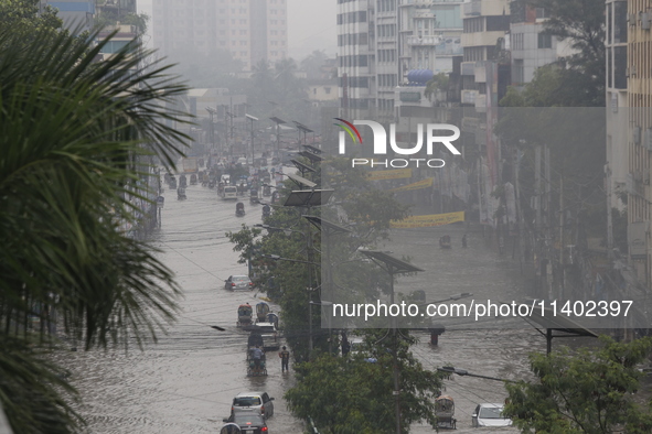 People are going through a flooded street after heavy monsoon rainfall in Dhaka, Bangladesh, on July 12, 2024. 