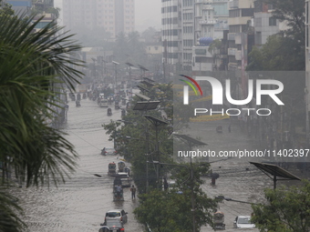 People are going through a flooded street after heavy monsoon rainfall in Dhaka, Bangladesh, on July 12, 2024. (