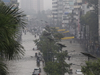 People are going through a flooded street after heavy monsoon rainfall in Dhaka, Bangladesh, on July 12, 2024. (