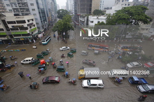 People are going through a flooded street after heavy monsoon rainfall in Dhaka, Bangladesh, on July 12, 2024. 