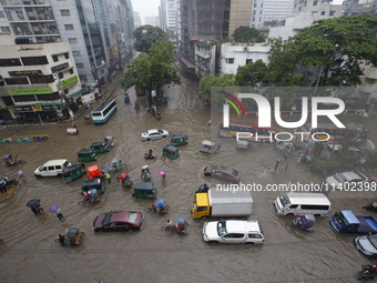 People are going through a flooded street after heavy monsoon rainfall in Dhaka, Bangladesh, on July 12, 2024. (