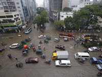 People are going through a flooded street after heavy monsoon rainfall in Dhaka, Bangladesh, on July 12, 2024. (