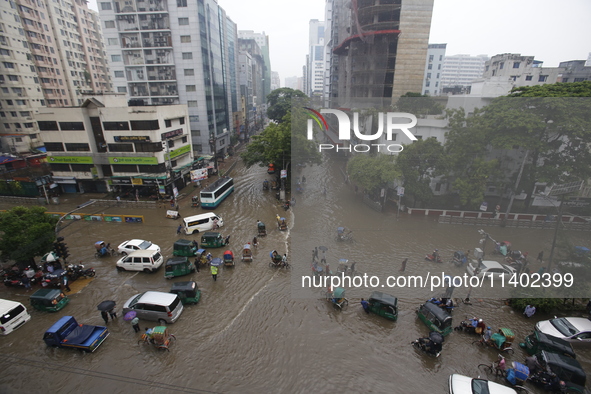 People are going through a flooded street after heavy monsoon rainfall in Dhaka, Bangladesh, on July 12, 2024. 