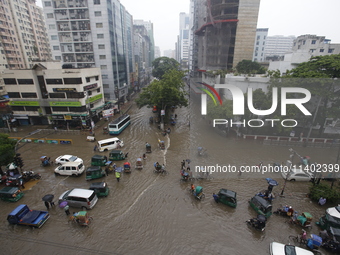 People are going through a flooded street after heavy monsoon rainfall in Dhaka, Bangladesh, on July 12, 2024. (